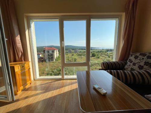 a living room with a coffee table and a large window at Laguna Sunset Appatments, sea and mountain view in Primorsko