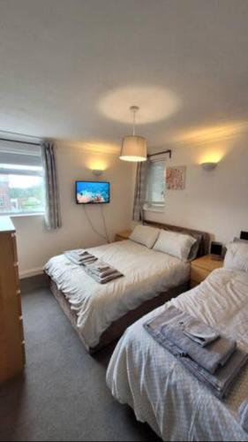 a bedroom with two beds and a flat screen tv at 4 Bedroom 4 En Suite House Close to A5 & Whipsnade in Luton