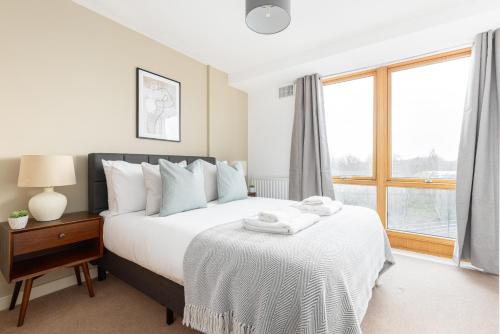 um quarto com uma cama com lençóis brancos e uma janela em The Highbury Collection em Londres