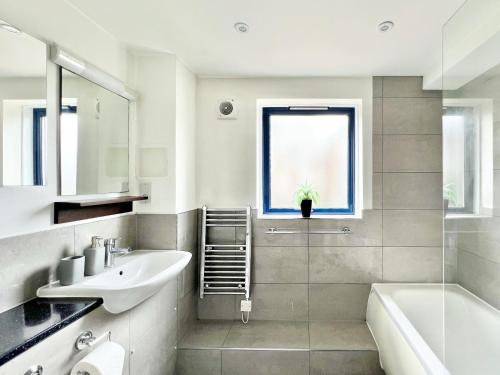 La salle de bains blanche est pourvue d'un lavabo et d'une baignoire. dans l'établissement WEEKLY OR MONTHLY STAY - Relocation & Business - 4 Guests - By Hofin Stays Short Lets & Serviced Accommodation, à Londres