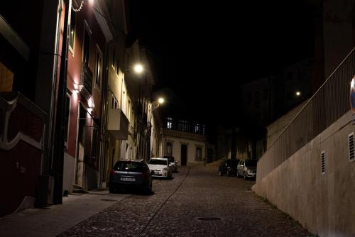 een donker steegje met auto's die 's nachts op straat geparkeerd staan bij Casa do Convento AL/141600 in Coimbra
