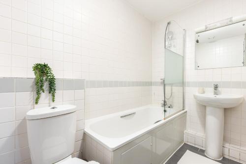 a white bathroom with a sink and a toilet and a tub at The Highbury Collection in London