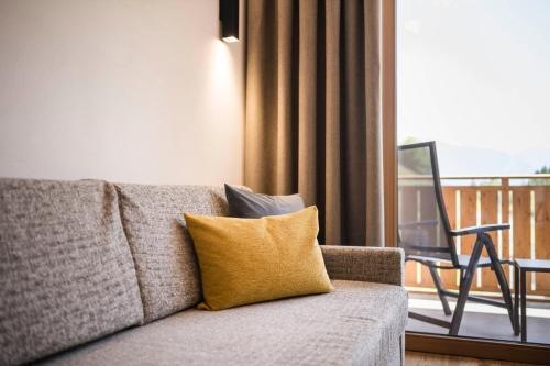 a couch with a yellow pillow next to a balcony at Gasthof Jaufensteg in Racines