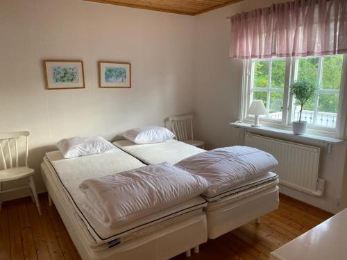 1 dormitorio con 2 camas y ventana en Trevlig och havsnära stuga, en Glommen