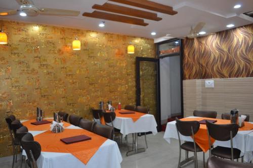 Un comedor con mesas y sillas y una pared. en Hotel Jigyasa By Mayda Hospitality Pvt. Ltd., en Agra