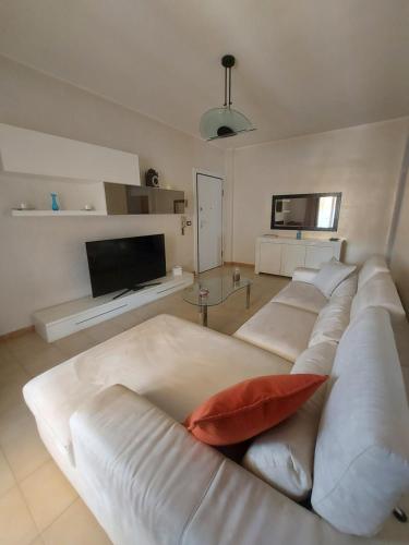 sala de estar con sofá blanco y TV en Moonhouse, en Ceglie Messapica