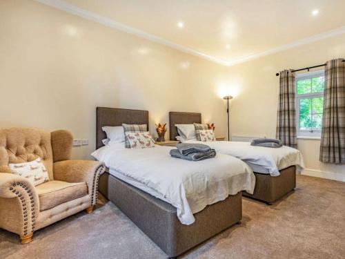 a bedroom with two beds and a chair and a window at Harefield Lodge in Pateley Bridge