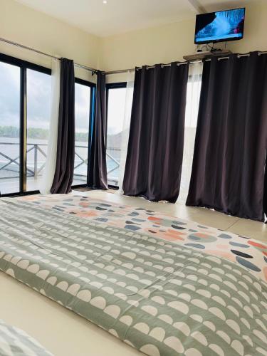 a bedroom with a large bed in front of windows at Villa Assinie Bord de Lagune in Assinie