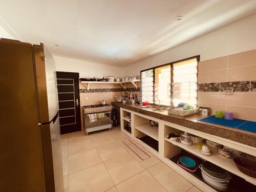 a large kitchen with a counter and a refrigerator at Villa Assinie Bord de Lagune in Assinie