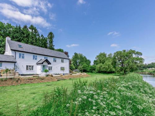 a white house with a grassy yard next to a river at Luxury Rural River Edge Retreat, Pet Friendly in Weare Giffard