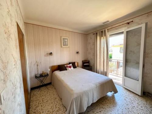 - une chambre avec un lit et une grande fenêtre dans l'établissement Appartement St Laurent, à Saint-Laurent-de-la-Salanque