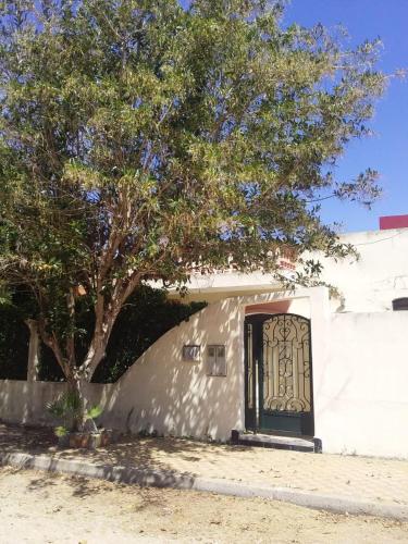 una porta su un edificio bianco con un albero di location de vacance sidi bouzid a Sidi Bouzid