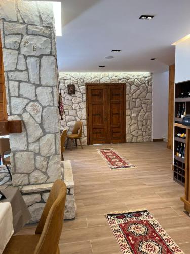 a living room with a stone wall and a wooden door at Oda N'Bjeshke in Valbonë