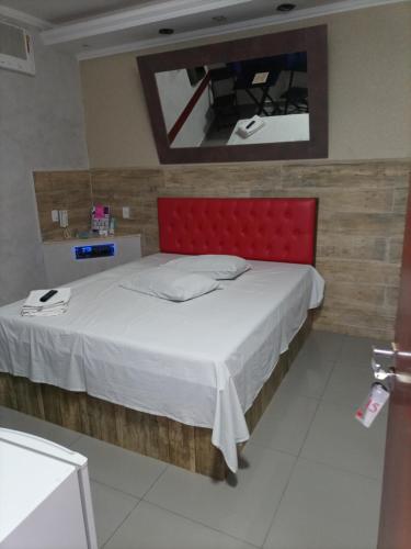 a bedroom with a large bed with a red headboard at Motel Vip Olimpia in Olímpia