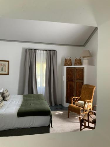 a bedroom with a bed and a chair and a window at Le Mas Les Eydins in Bonnieux