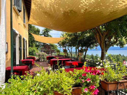 ein Restaurant mit roten Tischen und Blumen auf einer Terrasse in der Unterkunft Villa Schindler in Manerba del Garda