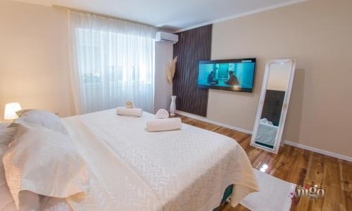 a bedroom with a white bed with a flat screen tv at Luxury Apartment Black and Gold in Mostar