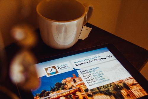 a cup of coffee sitting next to a tablet on a table at Relais nel Castello in Bassano del Grappa