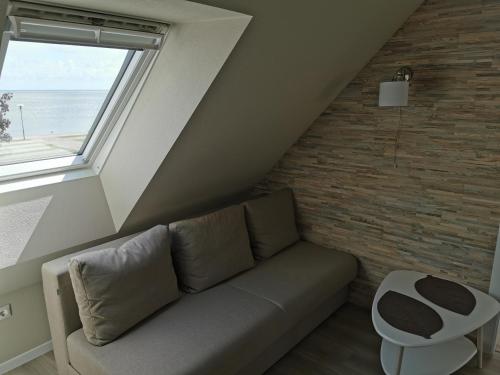 a living room with a couch and a window at Neringarent Apartamentai in Juodkrantė