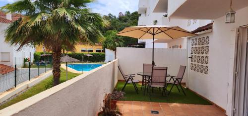 un balcón con mesa, sillas y una palmera en Bajo con Jardín Deluxe en Benahavís