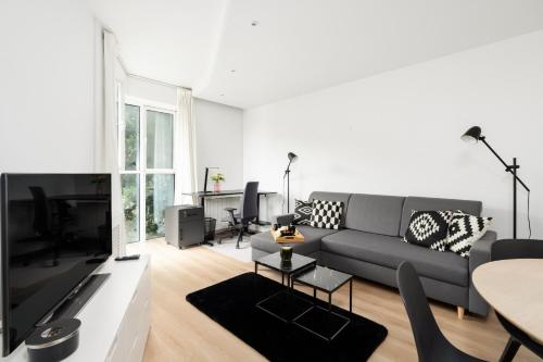 a living room with a couch and a tv at Cozy Black & White Studio in City Center with FREE GARAGE Poznań by Renters in Poznań