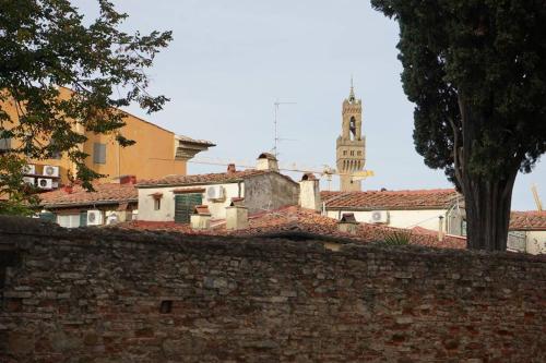 ein Gebäude mit einem Uhrturm hinter einer Ziegelwand in der Unterkunft Double Two de' Magnoli in Florenz