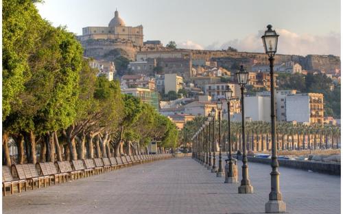 a street with benches and street lights in front of a city at Casa Vacanza - La Tartaruga in Milazzo