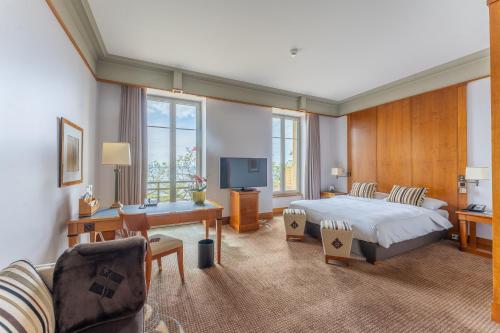 Schlafzimmer mit einem Bett, einem Schreibtisch und einem TV in der Unterkunft Beau Rivage Hotel in Neuenburg