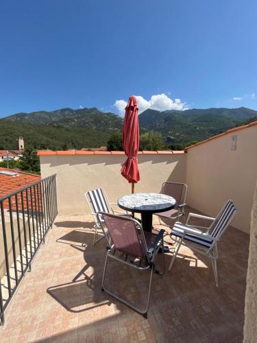 a patio with a table and chairs and an umbrella at Le mont canigou in Taurinya