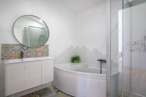 a white bathroom with a tub and a mirror at Charmante Chambre Privative in Bègles