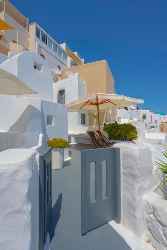 a patio with an umbrella and chairs and a house at Sophia Oia View in Oia