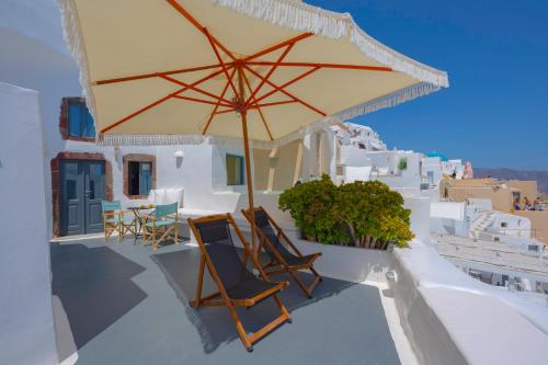 a patio with chairs and an umbrella on a building at Sophia Oia View in Oia