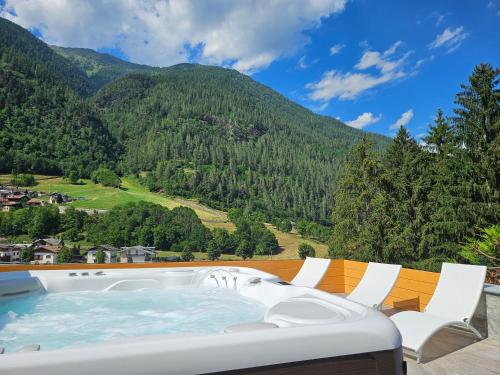 a hot tub on a deck with mountains in the background at Hotel Genzianella in Commezzadura