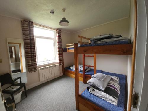 Cette chambre comprend 3 lits superposés et une fenêtre. dans l'établissement West Highland Lodge, à Kinlochleven