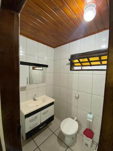a bathroom with a white toilet and a sink at Pousada Thamalu in Paraty
