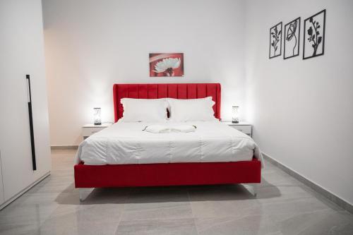 uma cama com uma cabeceira vermelha num quarto branco em 3S Tolo Apartments em Tolo