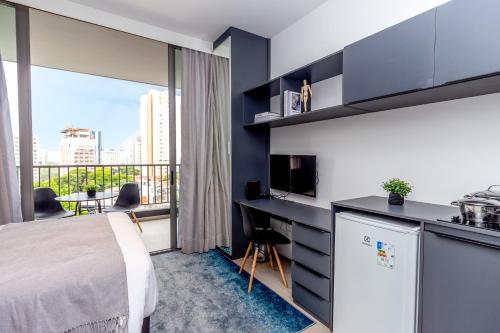 a bedroom with a bed and a desk and a balcony at 360 Suítes VN Turiassú by Housi - Apartamentos mobiliados in Sao Paulo