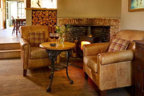 a living room with two chairs and a table with wine glasses at The Greyhound Inn in Wantage