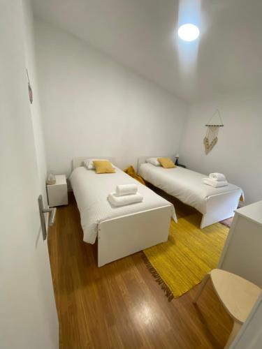 Habitación con 2 camas, paredes blancas y suelo de madera. en S&C HOSTING en Celorico de Basto