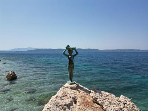 a statue of a woman standing on a rock in the water at Sobe Kraft 1 in Živogošće