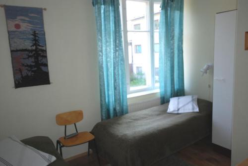 1 dormitorio con 1 cama y una ventana con cortinas azules en Jämsän Gasthaus, en Jämsä