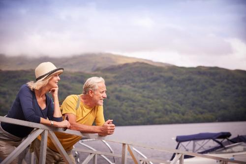 a man and woman standing on a bridge over a lake at Loch Lomond Holiday Park in Inversnaid