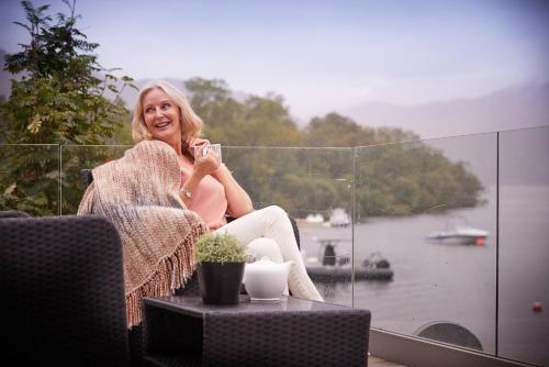 a woman sitting on a balcony talking on a cell phone at Loch Lomond Holiday Park in Inversnaid