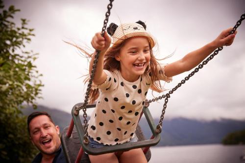 a little girl is sitting on a swing at Loch Lomond Holiday Park in Inversnaid