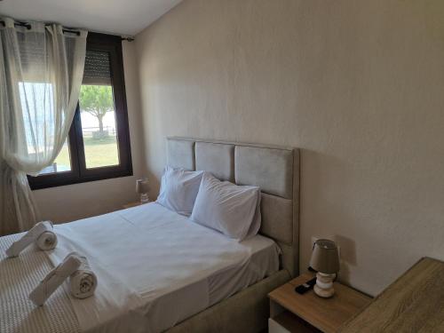 a bedroom with a bed with white sheets and a window at On the wave studios Spitakia sto kyma in Nikiti