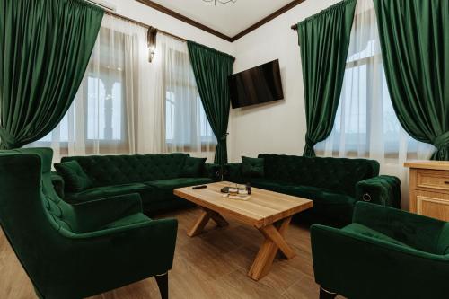 una sala de estar con sofás verdes y una mesa de madera. en Pensiunea Tara Codrului, en Asuaju de Sus
