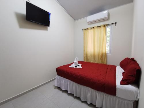 a bedroom with a red bed and a television at Casa El Cipres Residencial Privada in Santo Tomás