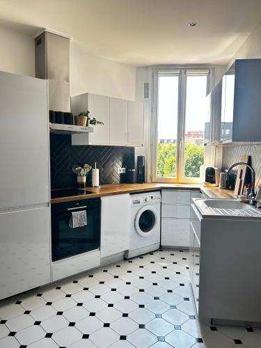 eine weiße Küche mit einer Waschmaschine und einem Fenster in der Unterkunft Appartement charmant et lumineux ! in Boulogne-Billancourt
