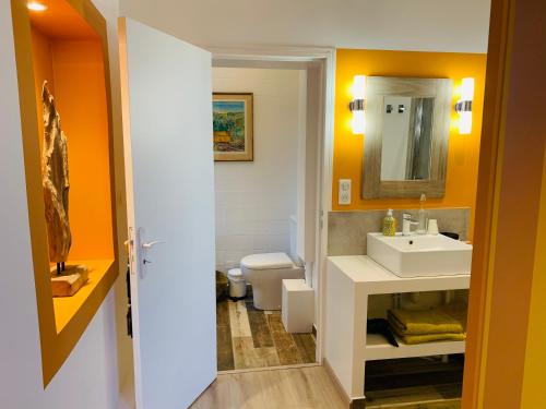 a bathroom with a sink and a toilet and a mirror at Aux couleurs de Commarin in Commarin