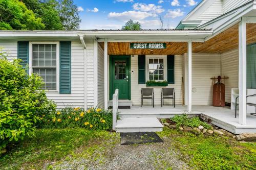 una pequeña casa blanca con una puerta verde en Long Trail Suite at The Bridgewater Inn, en Bridgewater